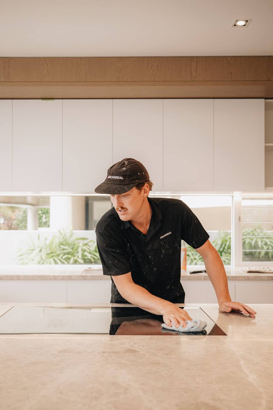 ARCHISEAL technician wiping down a stone benchtop after sealing