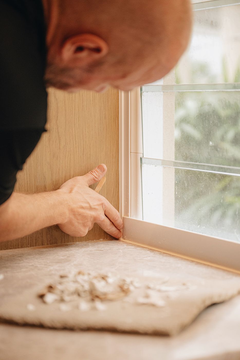 ARCHISEAL technician tooling a silicone joint at a window reveal
