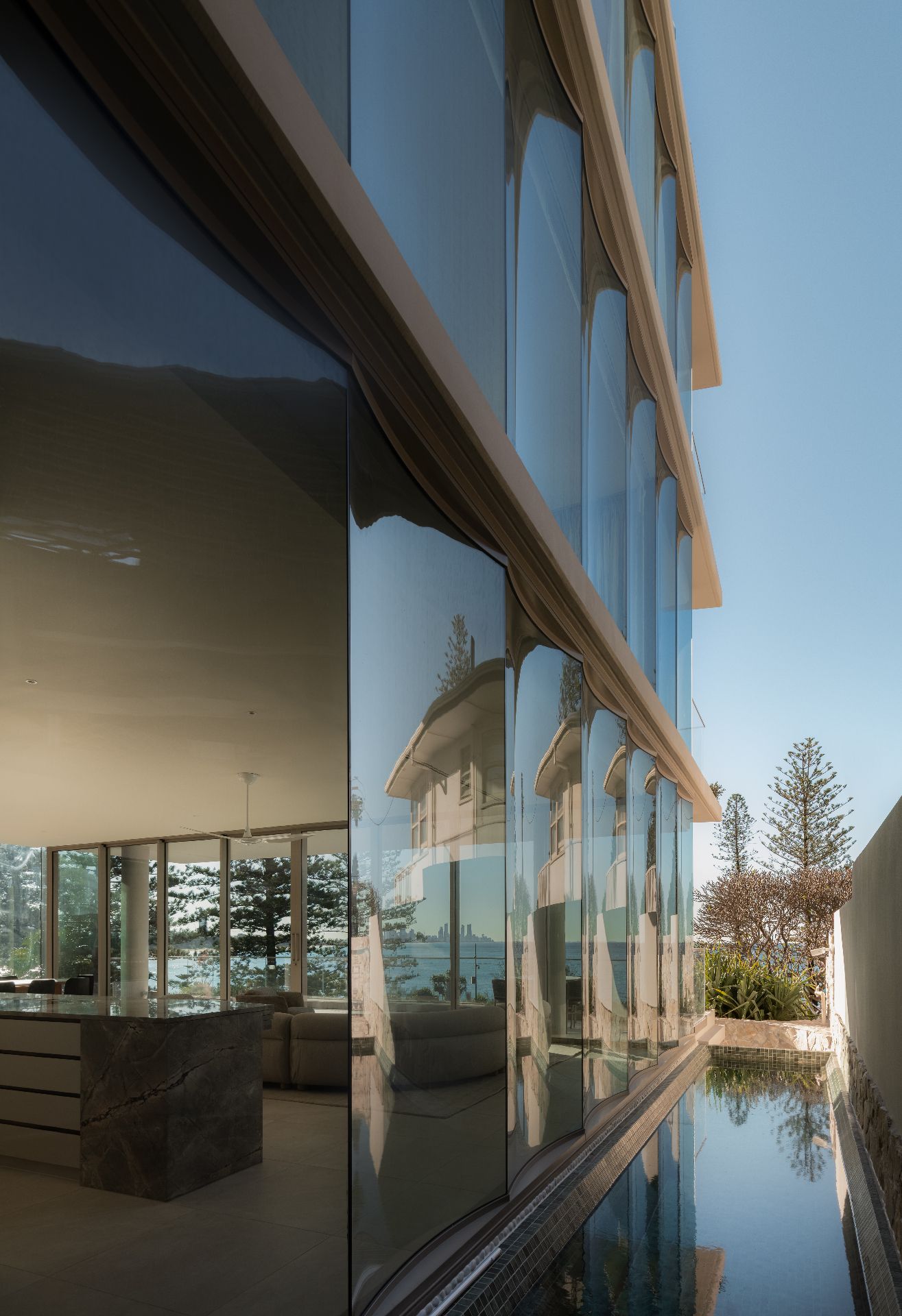 Curved glass facade of a beachfront residence with pool